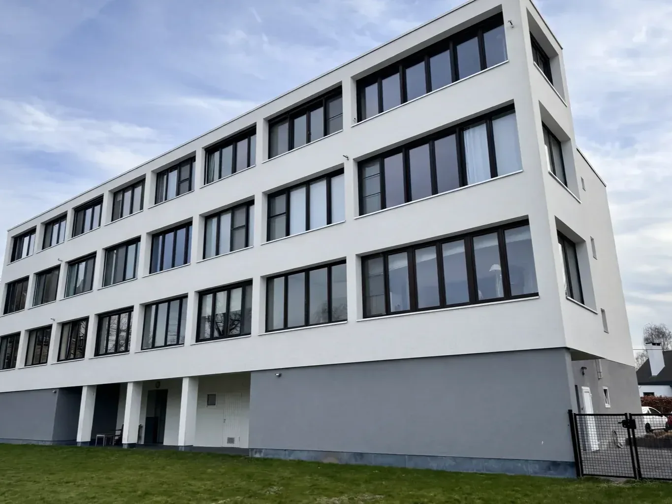 Hetzelfde appartementsgebouw na reiniging: helder witte crepi over vier bouwlagen