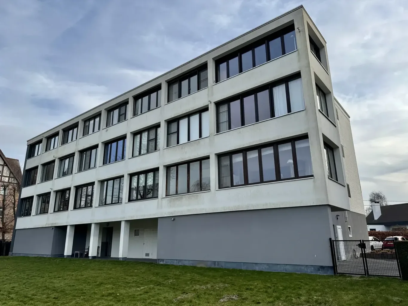 Appartementsgebouw met witte crepi, grijsgroene aanslag onder de raambanden, vóór reiniging